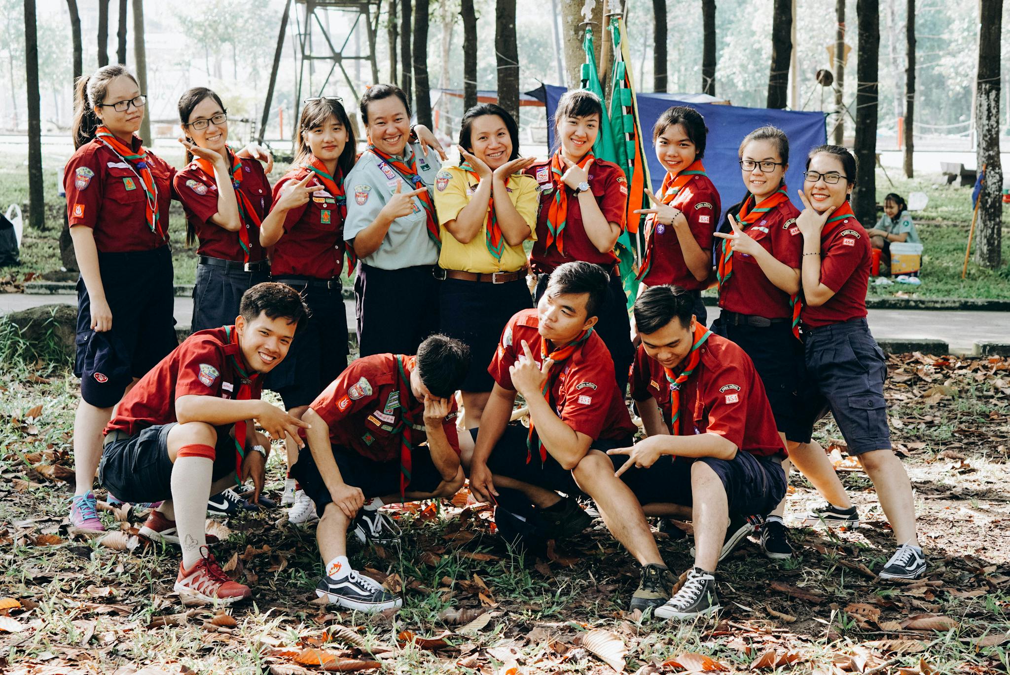 A group of young scouts posing playfully outdoors with their uniforms and badges.