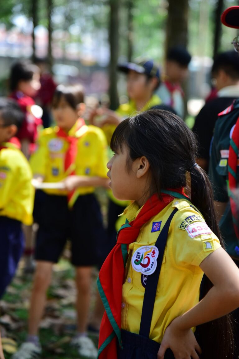 Children in yellow scout uniforms participating in an outdoor event with scout leaders.
