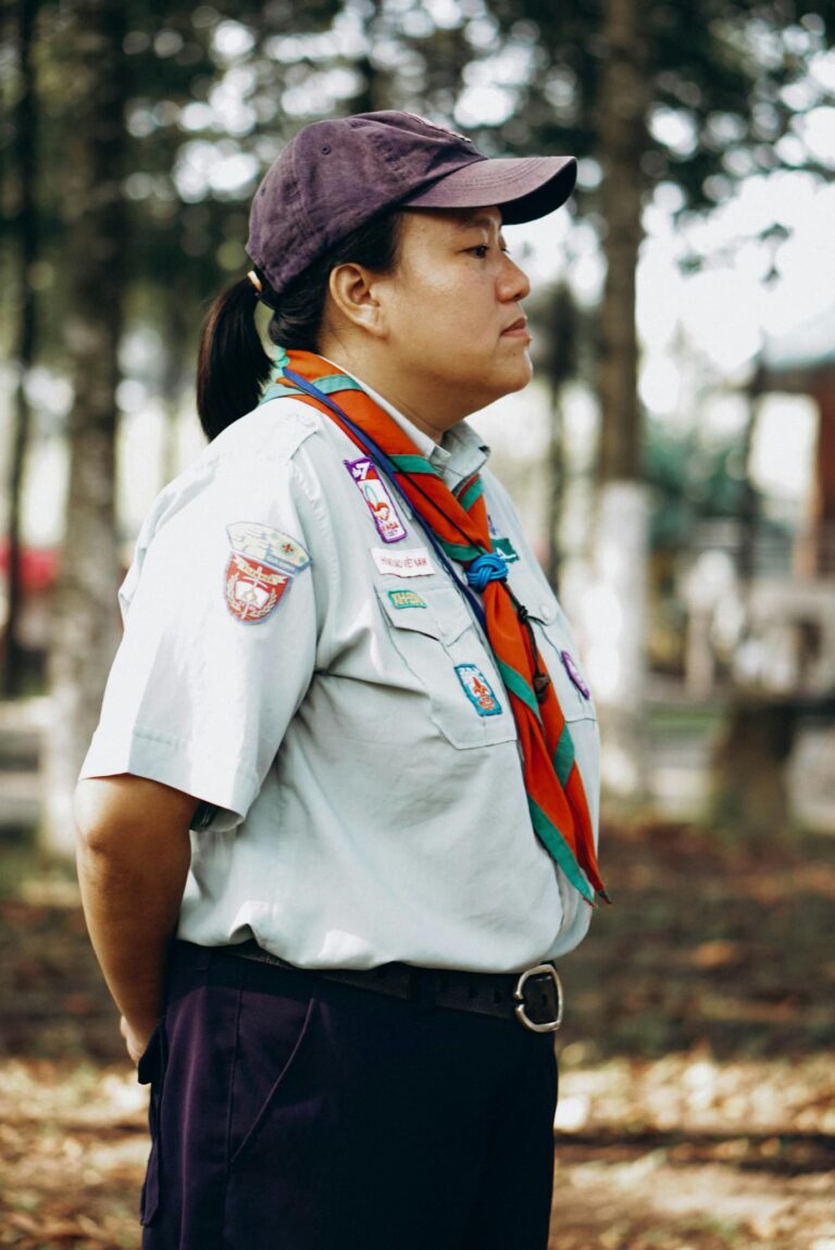 Profile of a scout leader standing in a forest, in uniform with badges.
