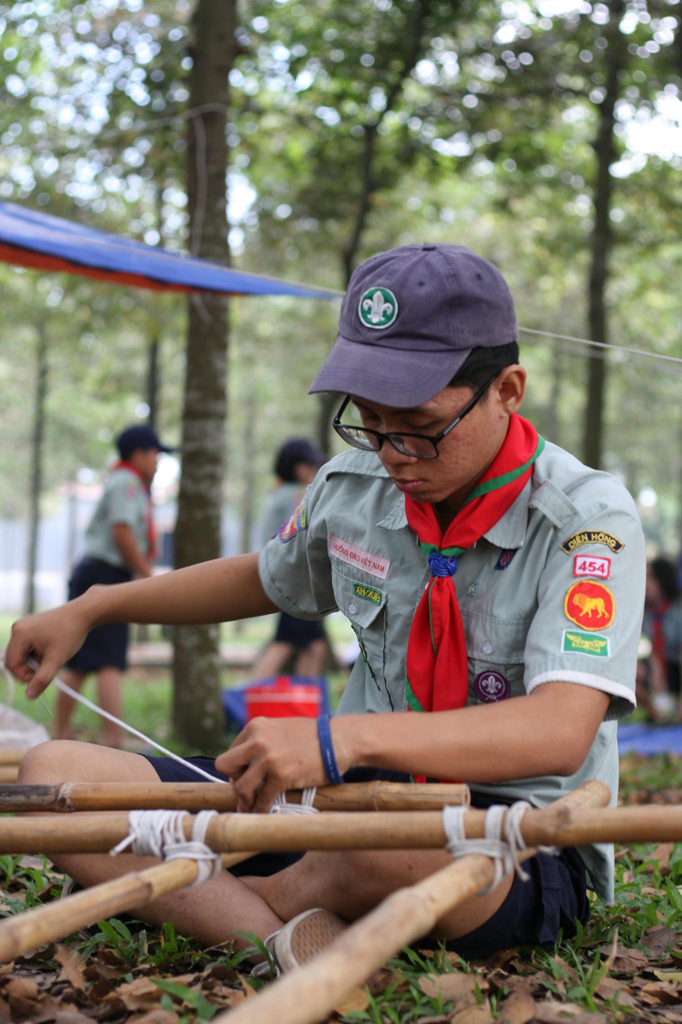 Scout in uniform practicing knot tying during outdoor camping activities.