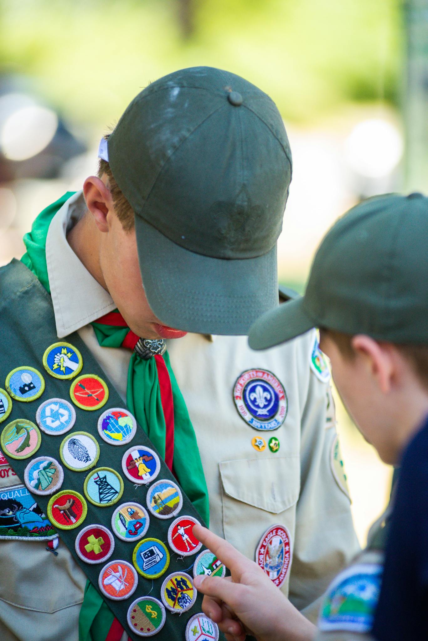 Two Boy Scouts examine merit badges on a sash, emphasizing achievements.