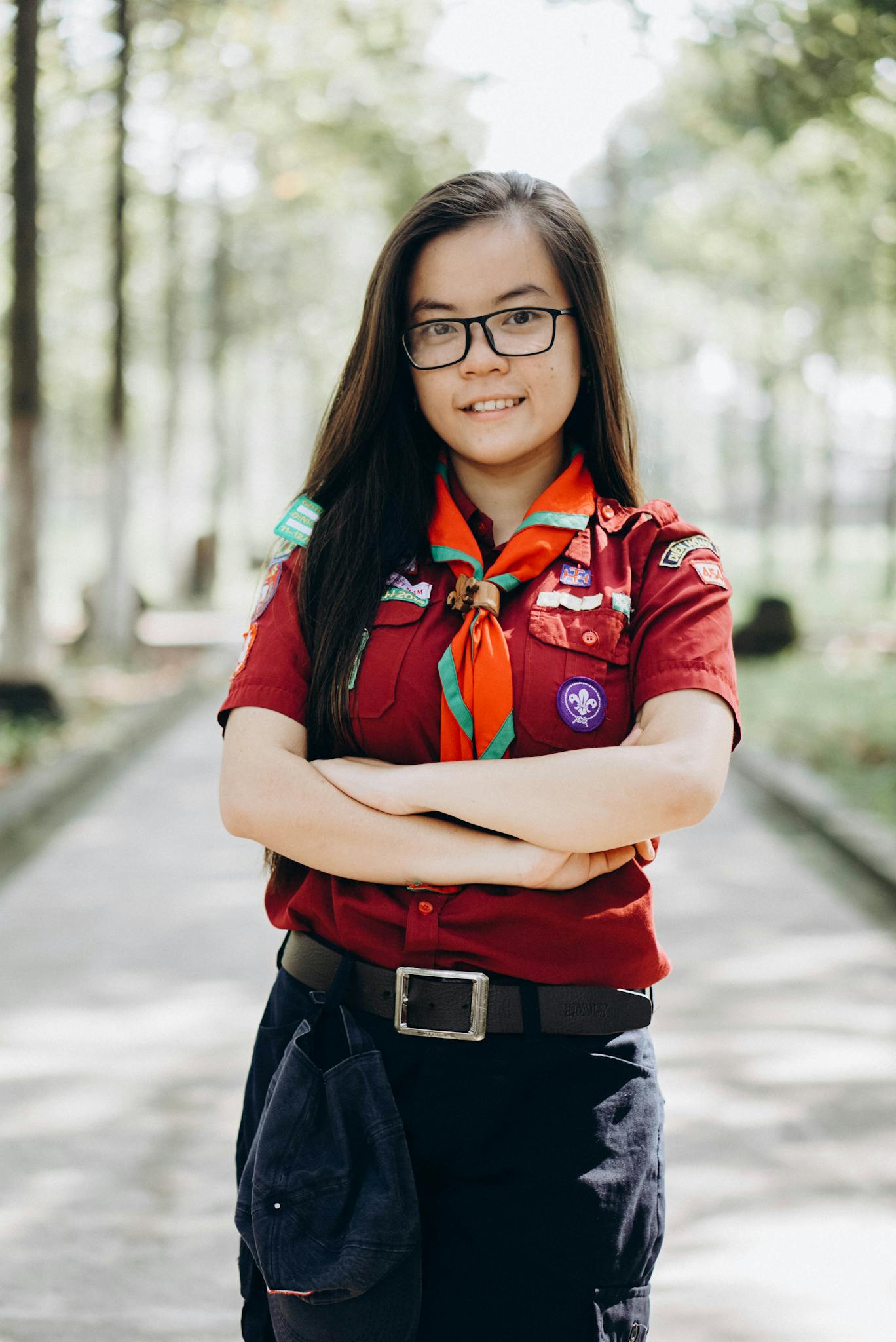 Young girl scout confidently posing outdoors in uniform, embodying leadership and teamwork.
